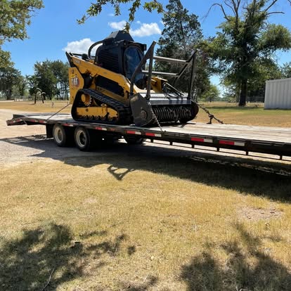 Compact track loader with forestry mulcher on trailer for land clearing work